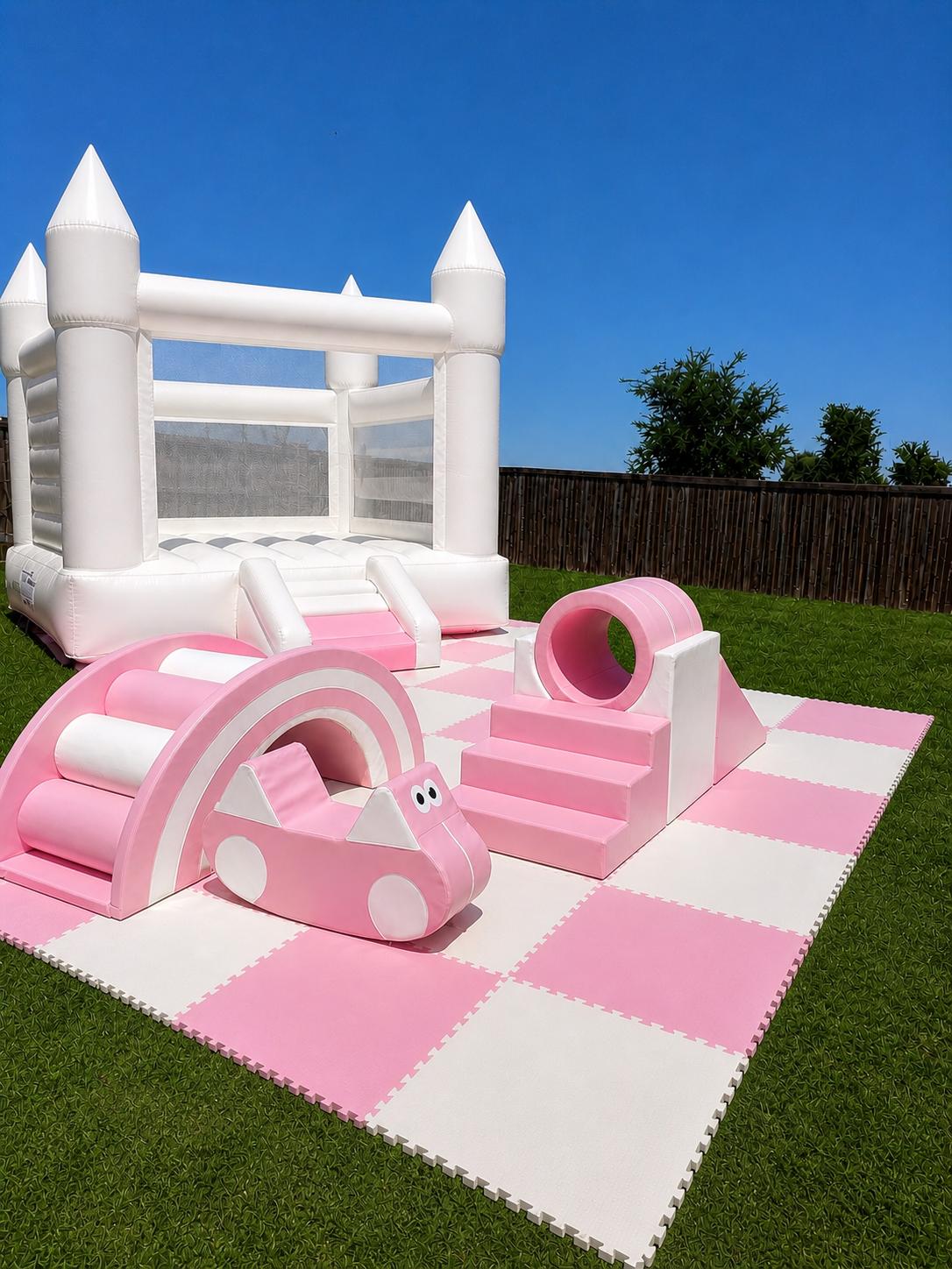 Pink soft play setup with a white bounce house and padded play pieces.