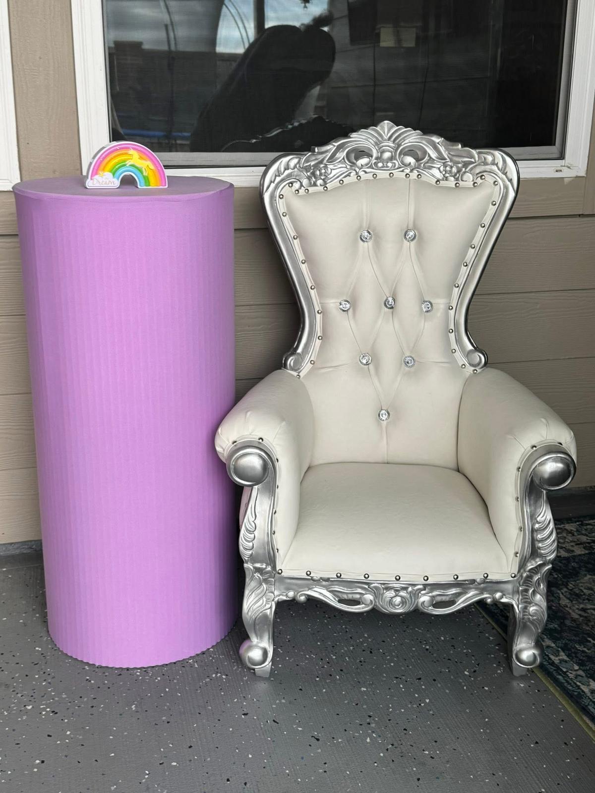 White and silver throne chair beside a purple pedestal stand.